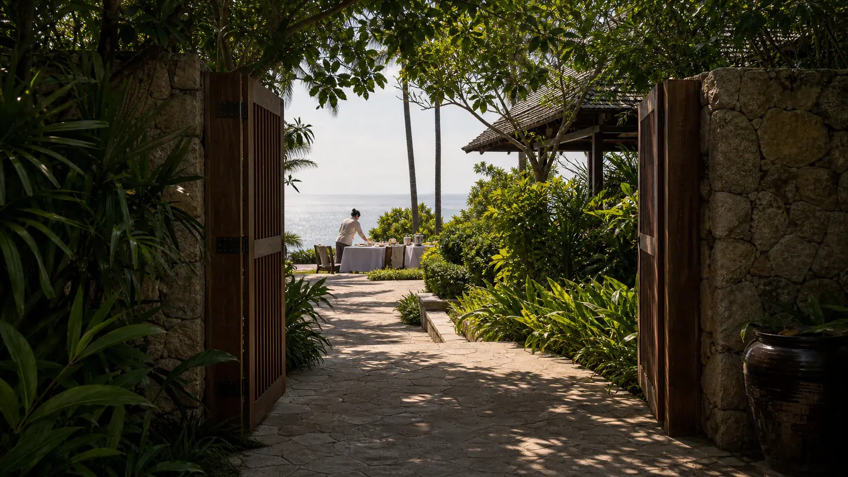 Phuket Estates vs. Amanpuri shown as secluded Phuket estate gate arrival for VIAIVE, with private gate, local stone, villa staff preparation.