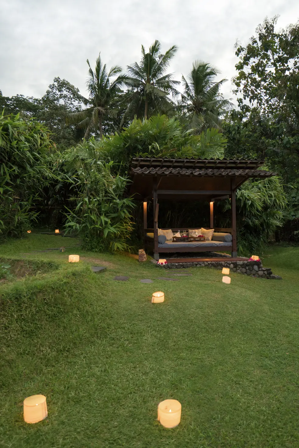 A private dinner set in Amanjiwo's Gubuk Sawah rice-field pavilion at dusk.