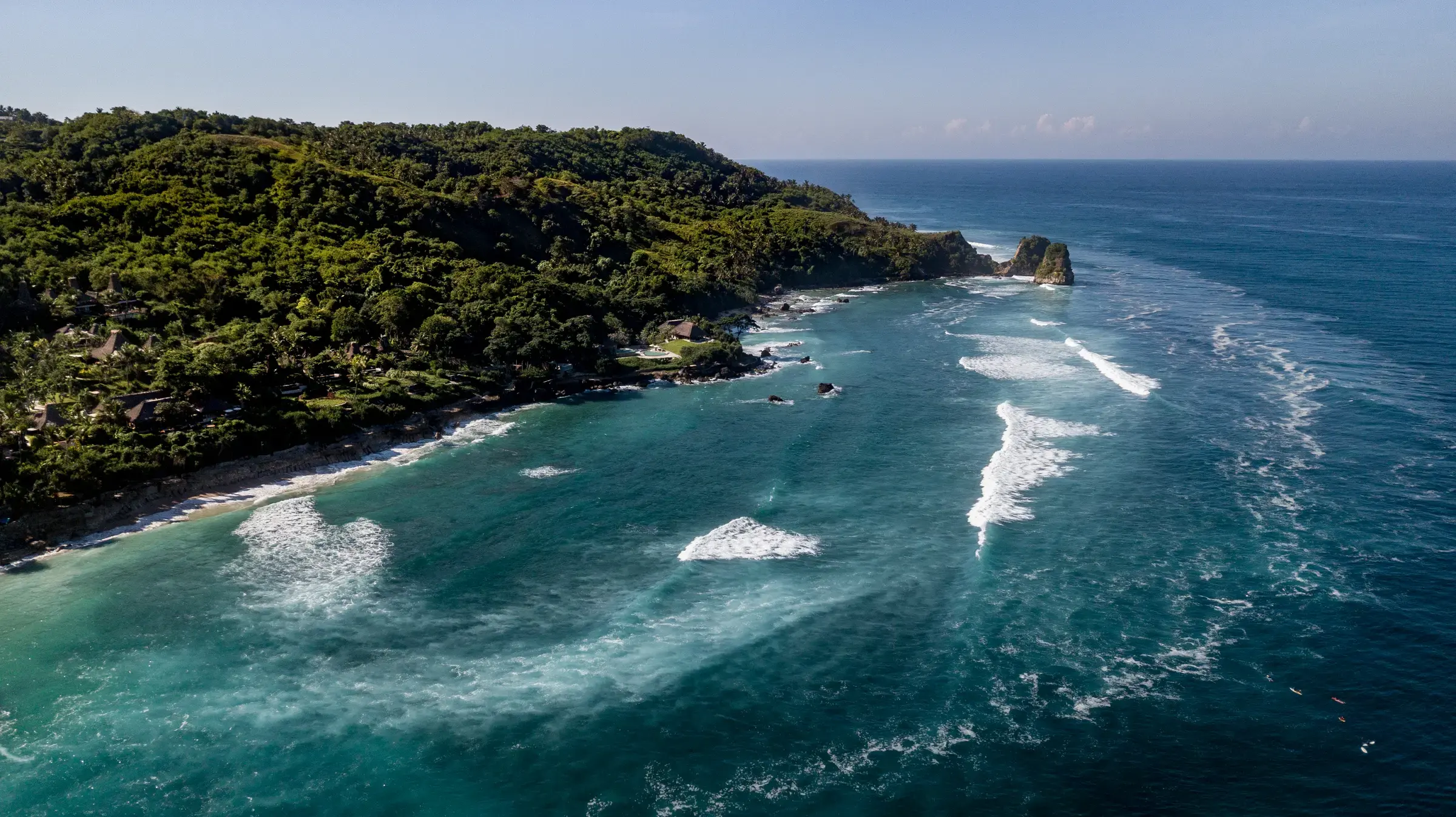 Aerial view of NIHI Sumba's forested coastal cliffs above the Indian Ocean
