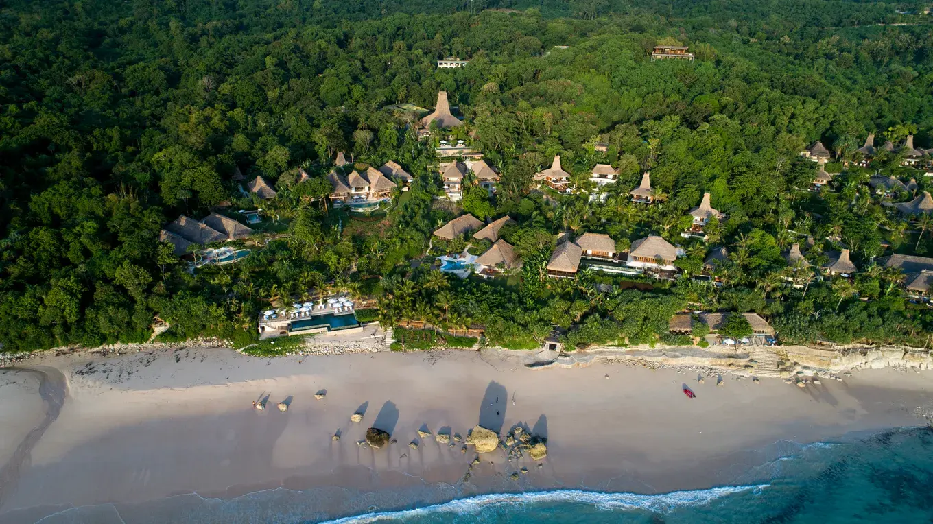 Aerial view of NIHI Sumba's resort buildings set among the beachfront jungle