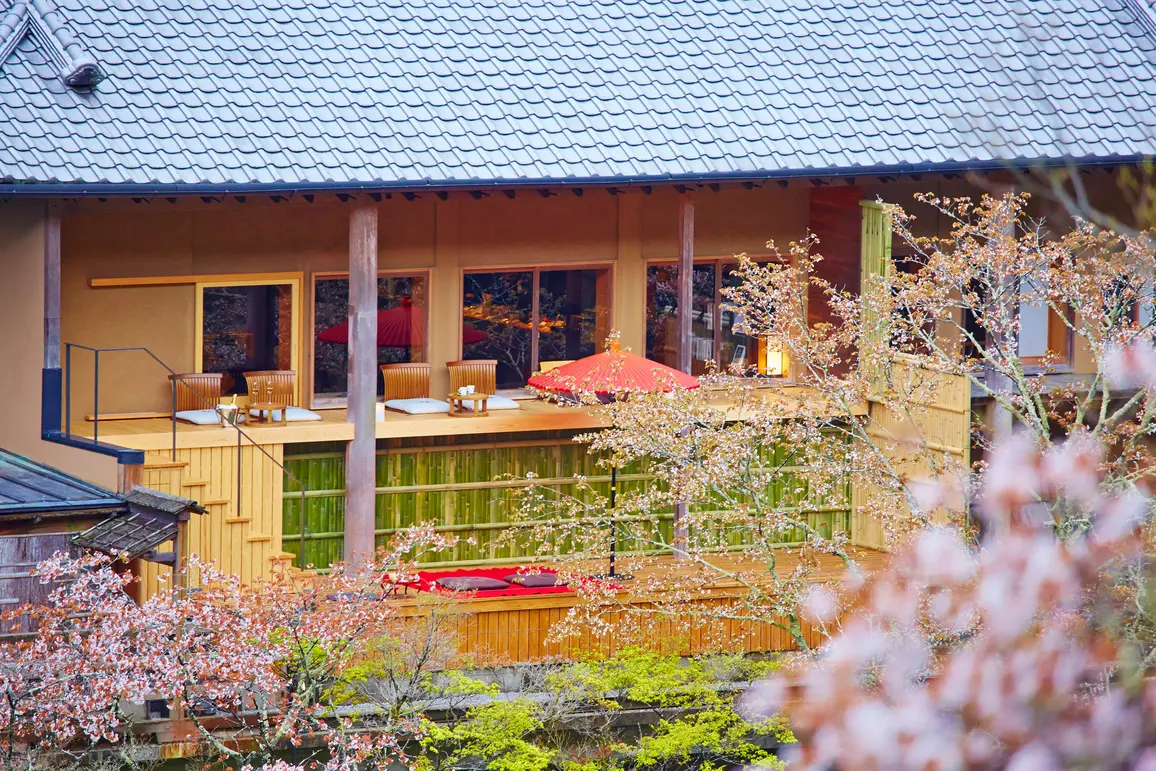HOSHINOYA Kyoto's floating tea room and open terrace framed by spring blossoms.