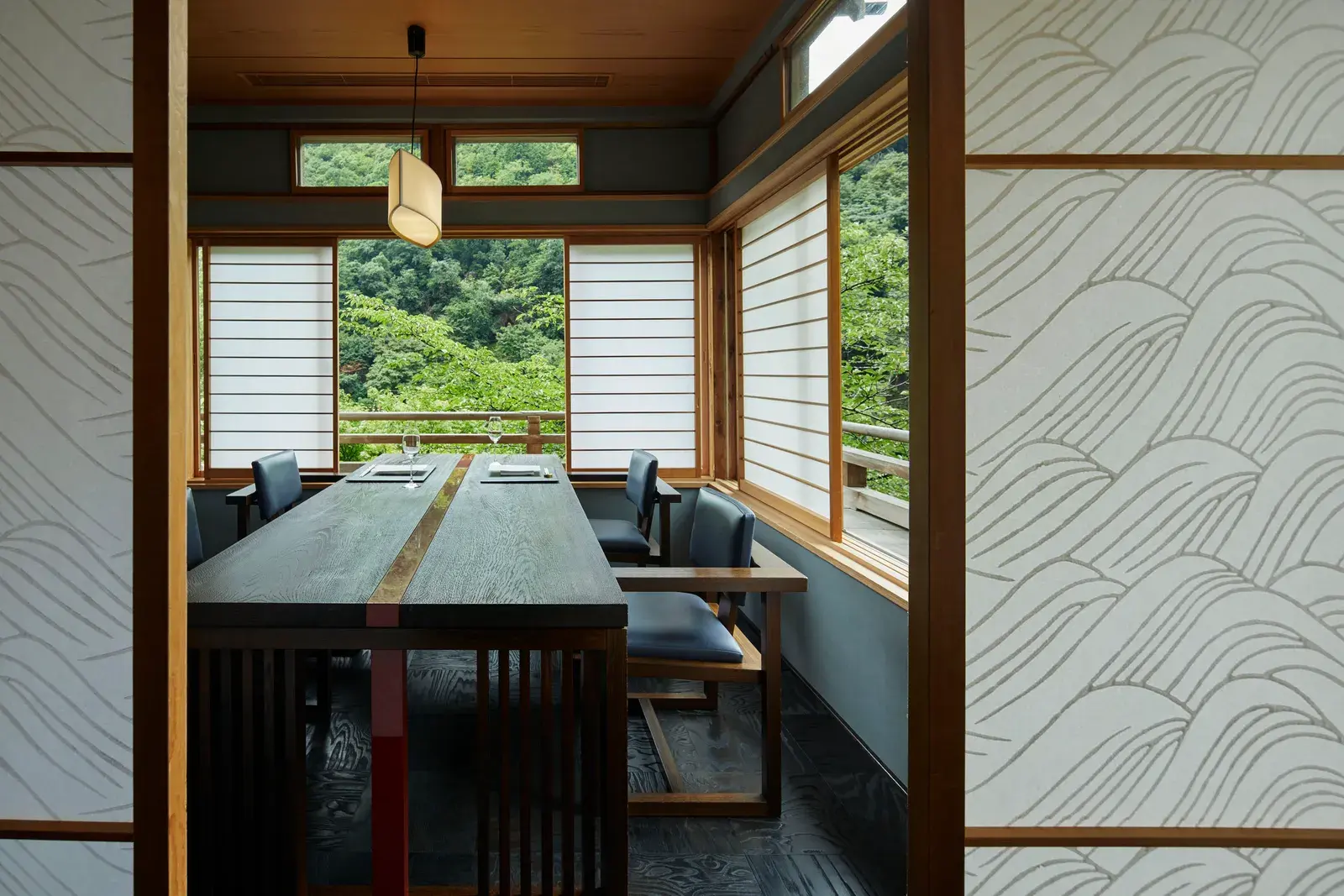 A private dining room at HOSHINOYA Kyoto with shoji screens and forest views.
