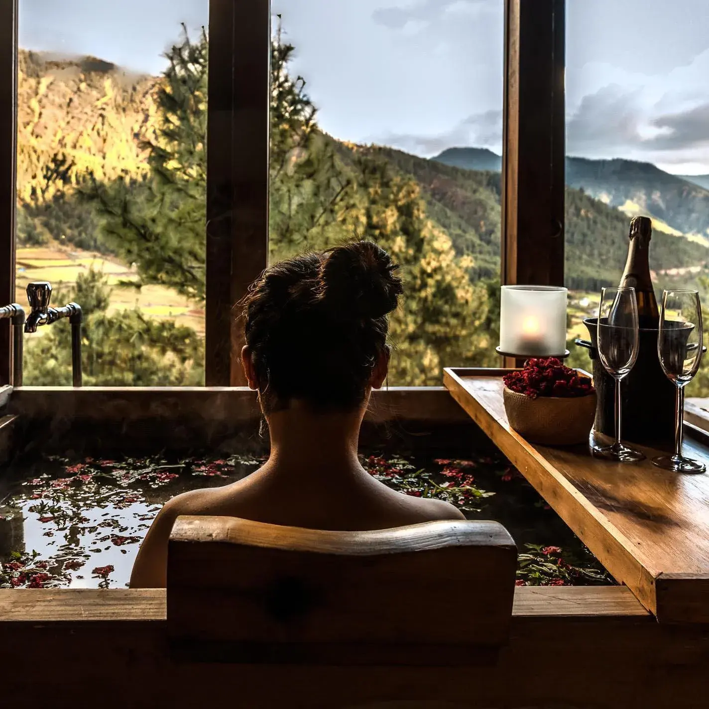 An outdoor bath at andBeyond Punakha River Lodge looking out over the Punakha valley at dusk.