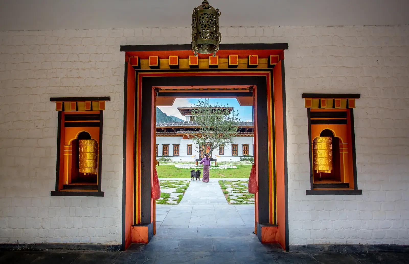 Traditional Bhutanese entrance archway at Bhutan Spirit Sanctuary with gilded prayer wheels opening onto the courtyard