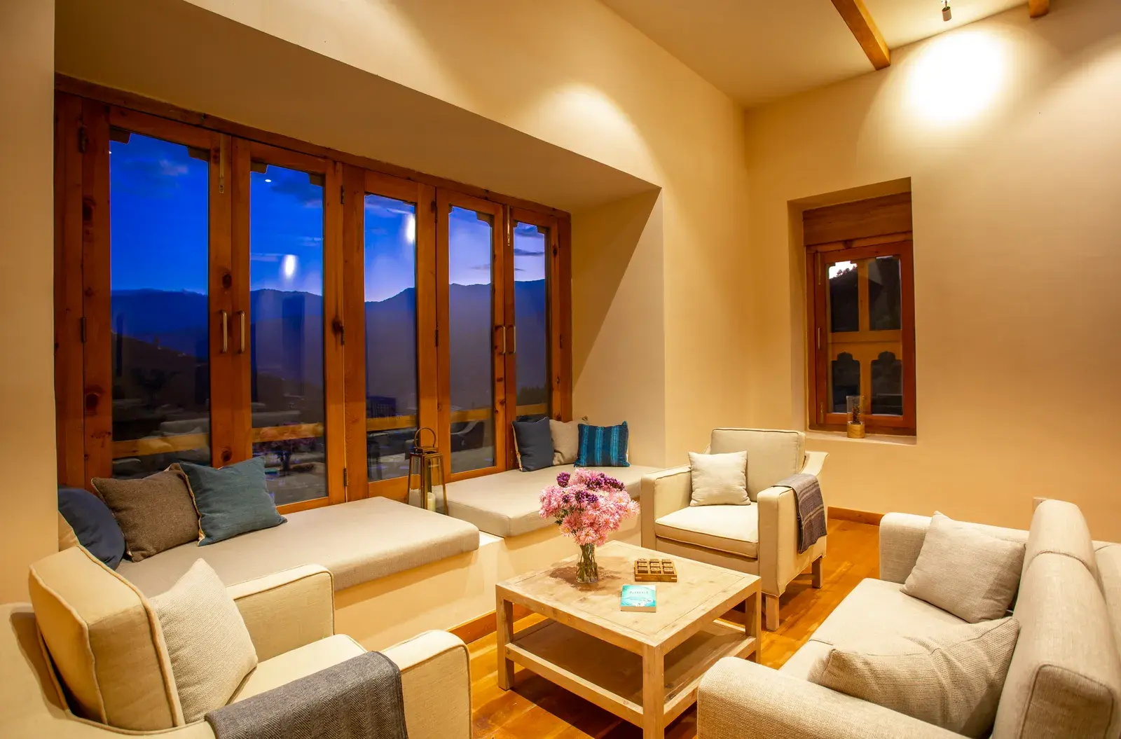 Lounge seating area at Bhutan Spirit Sanctuary with floor-to-ceiling windows overlooking the valley at dusk