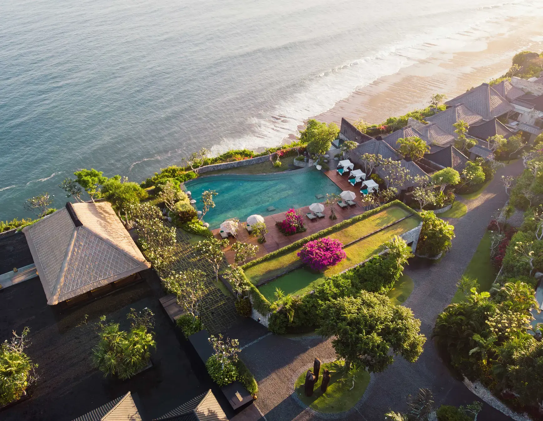 Aerial sunset view of Bulgari Resort Bali's clifftop pool over the Indian Ocean