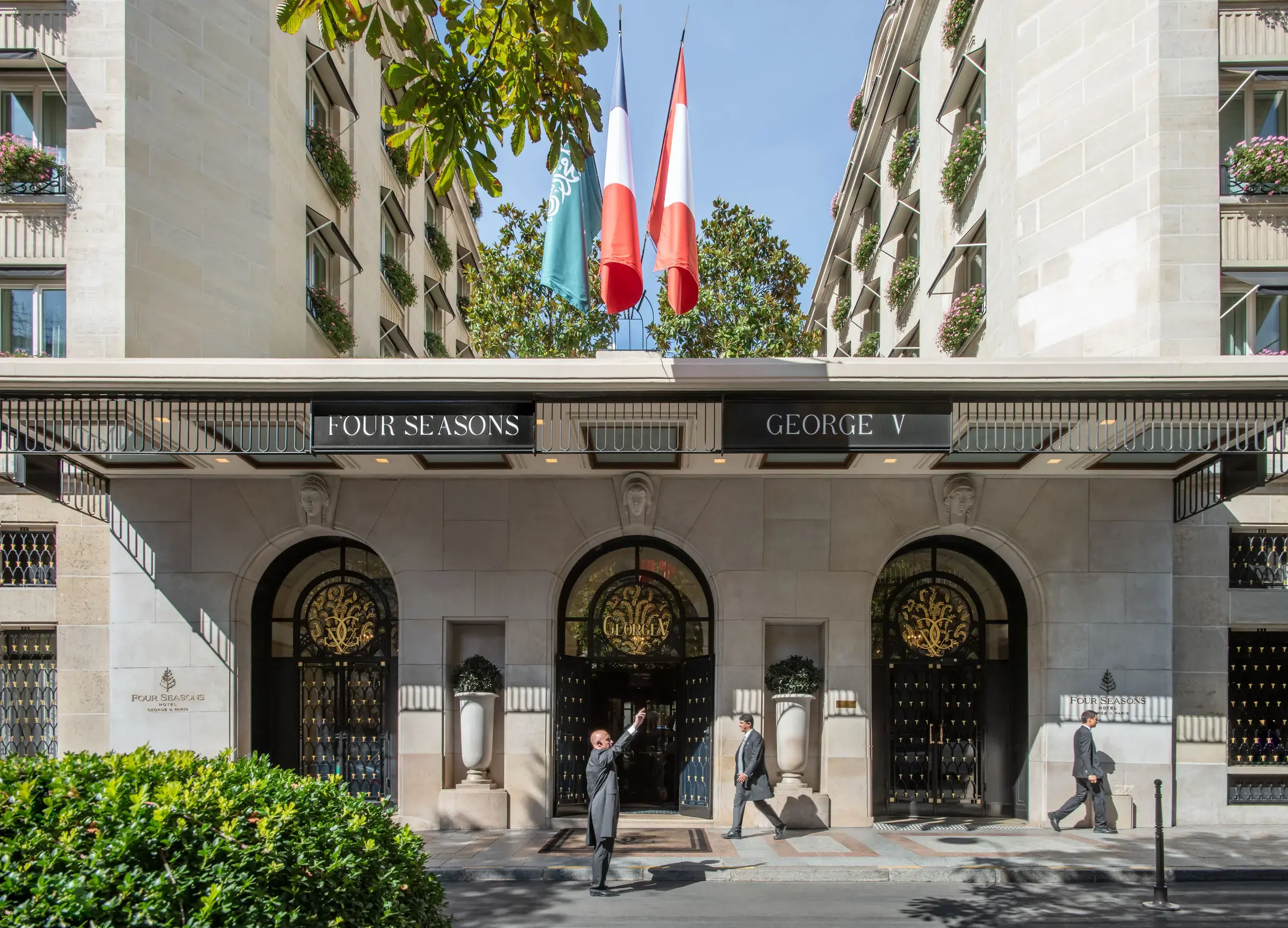 The 1928 Art Deco facade of Four Seasons Hotel George V on avenue George V, with its awninged stone entrance, clipped topiary and Four Seasons flags