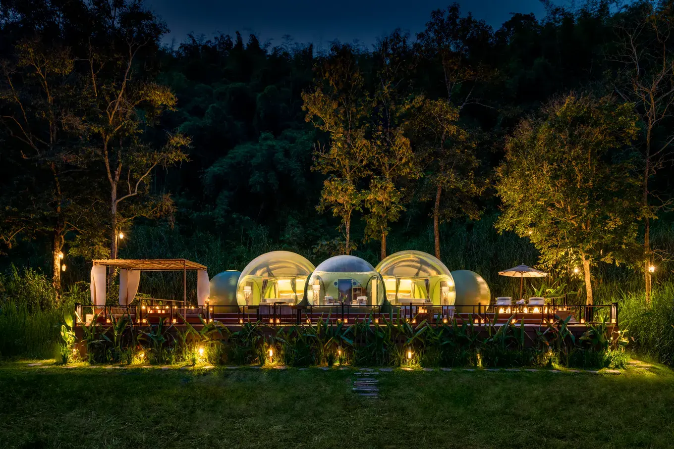 Jungle bubble tents lit at dusk at Anantara Golden Triangle Elephant Camp & Resort