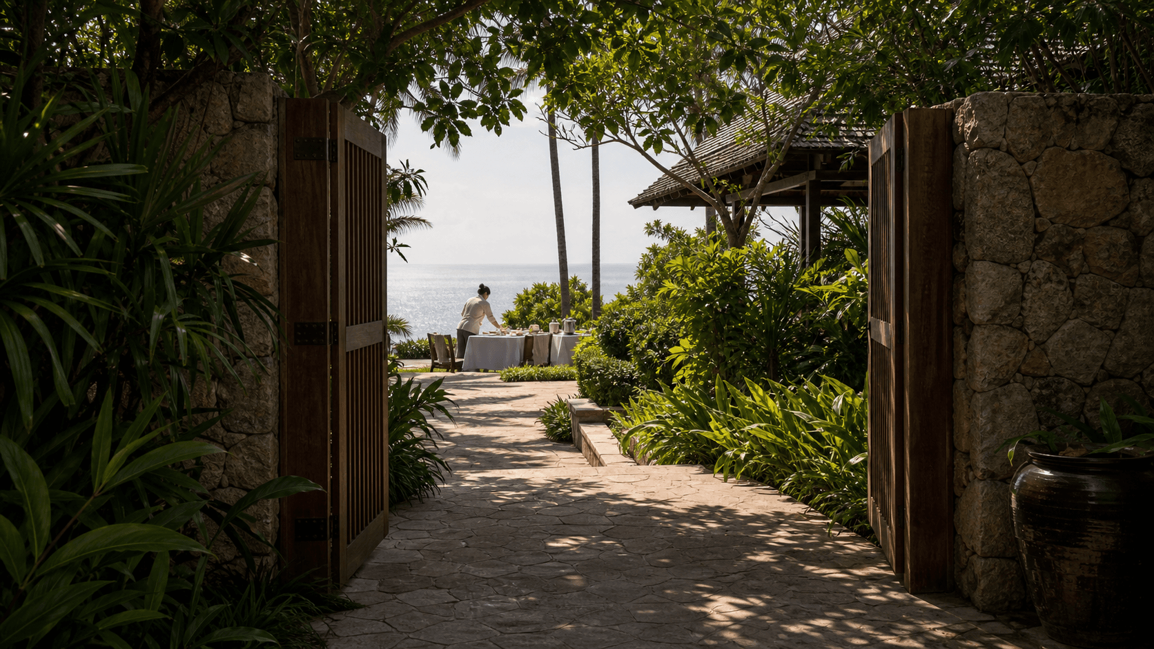 Amanpuri-style Phuket estate gate arrival with private stone gate and tropical planting.