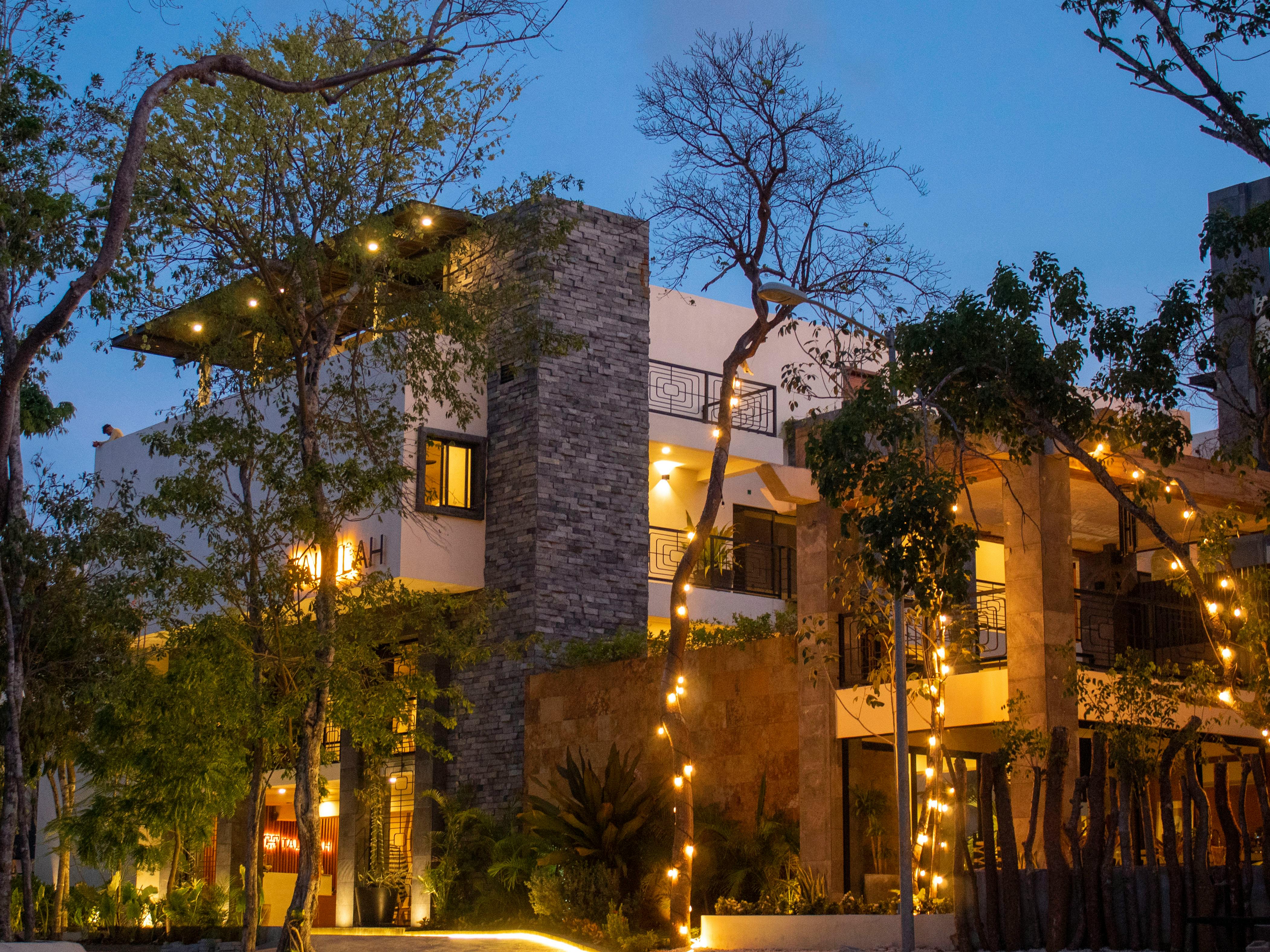 Hotel exterior at dusk with warm interior light and a restrained arrival atmosphere