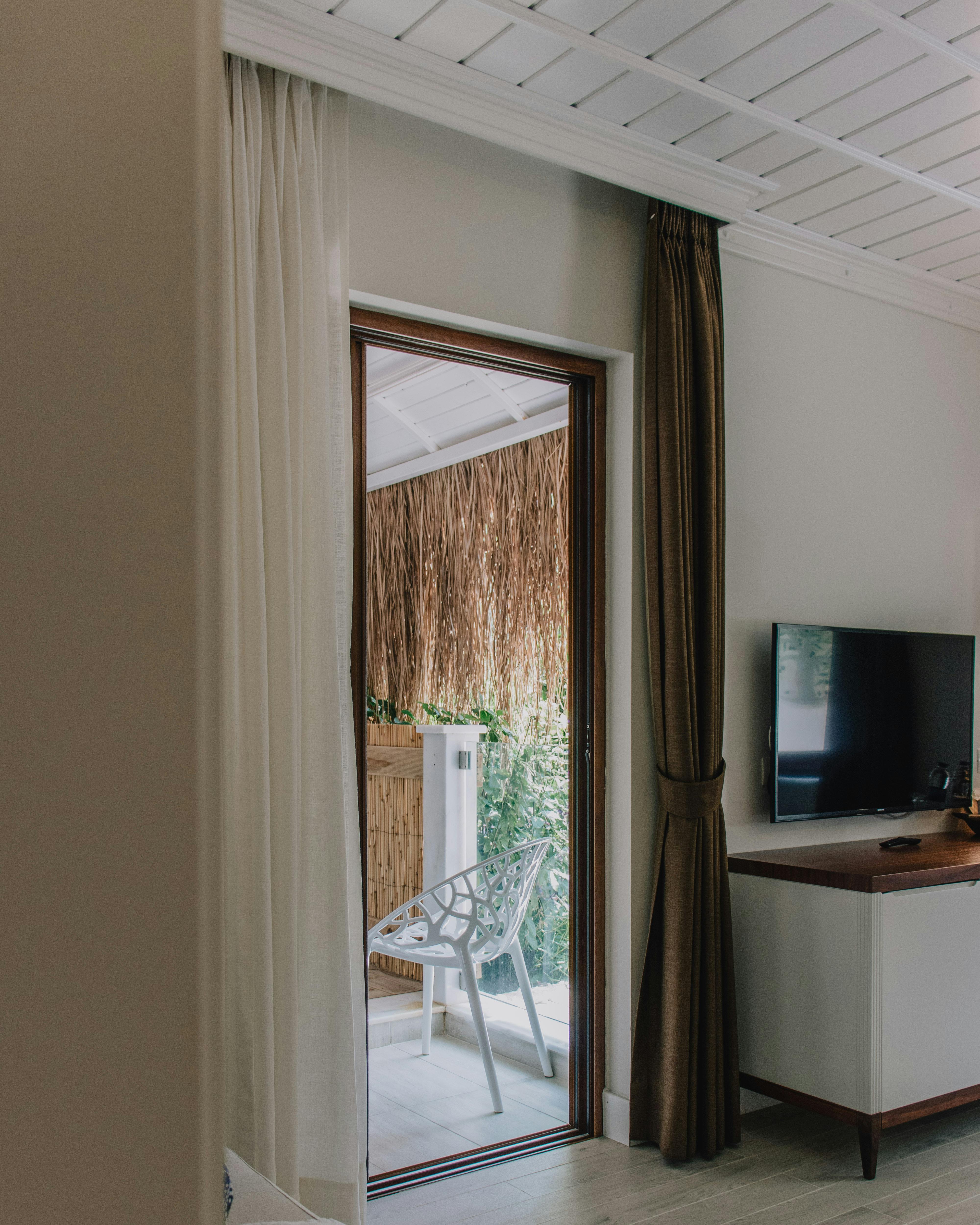 Quiet suite interior with balcony access, curtains, and soft natural light